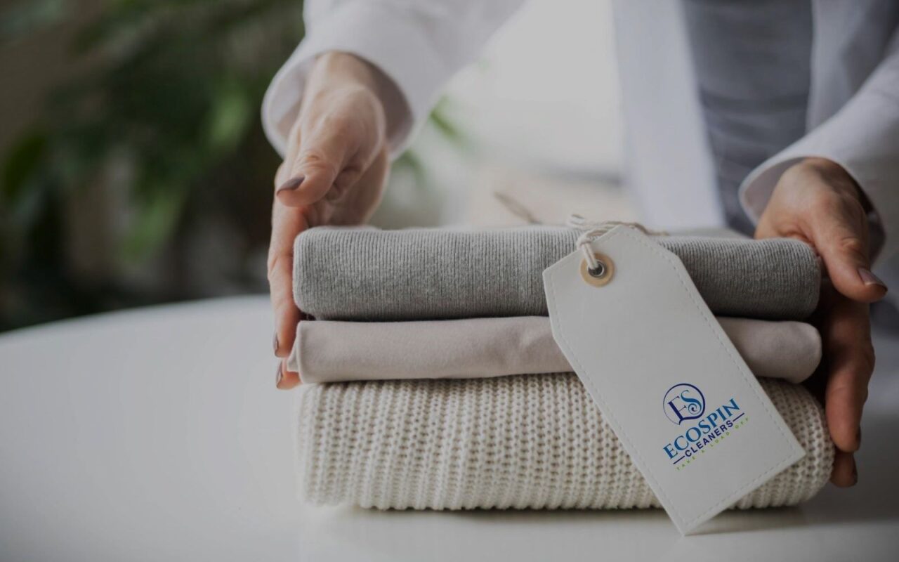 A stack of clean, folded laundry with a flower, representing Ecospin's sustainable and eco-friendly laundry services.